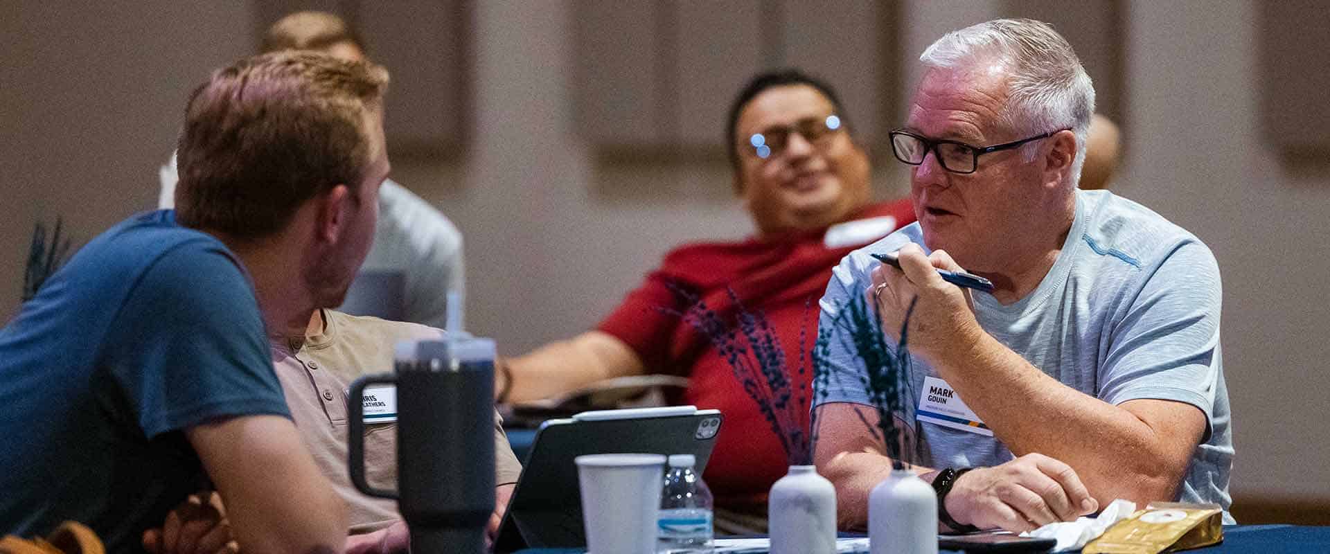 Building-Bridges-Aligning-Church-Cultures-in-a-Merger-Context-Header-Image group of men talking at a table
